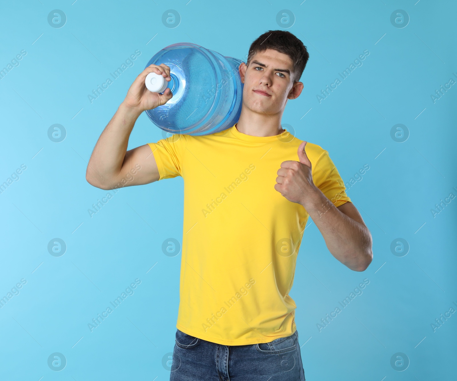 Photo of Delivery man with cooler bottle of water showing thumbs up on light blue background