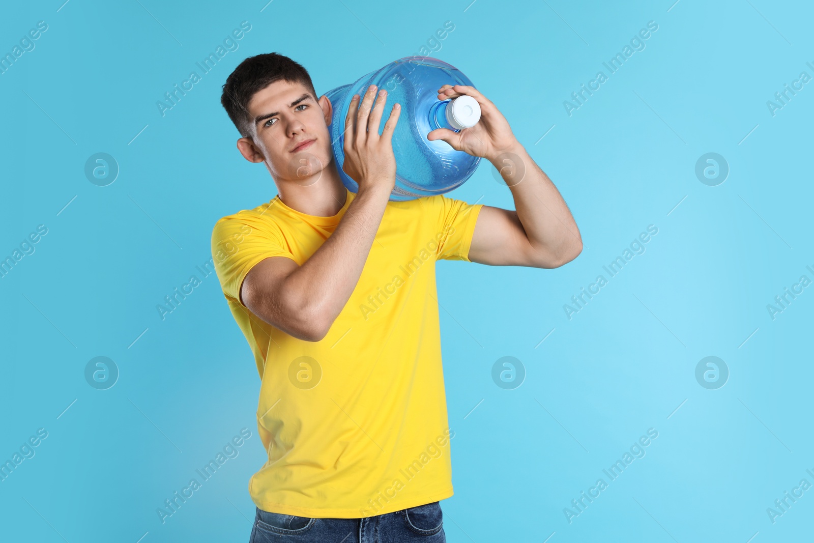 Photo of Delivery man with cooler bottle of water on light blue background
