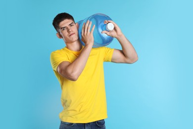 Photo of Delivery man with cooler bottle of water on light blue background