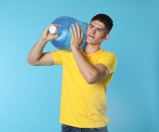 Photo of Delivery man with cooler bottle of water on light blue background
