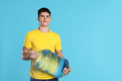 Photo of Delivery man with cooler bottle of water on light blue background. Space for text