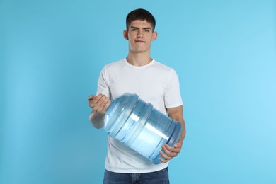 Photo of Delivery man with cooler bottle of water on light blue background
