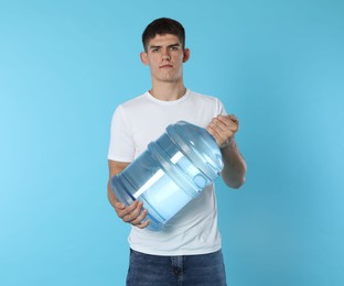 Photo of Delivery man with cooler bottle of water on light blue background