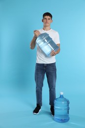 Photo of Delivery man with cooler bottles of water on light blue background