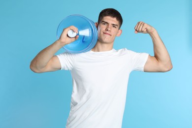 Photo of Delivery man with cooler bottle of water showing his biceps on light blue background