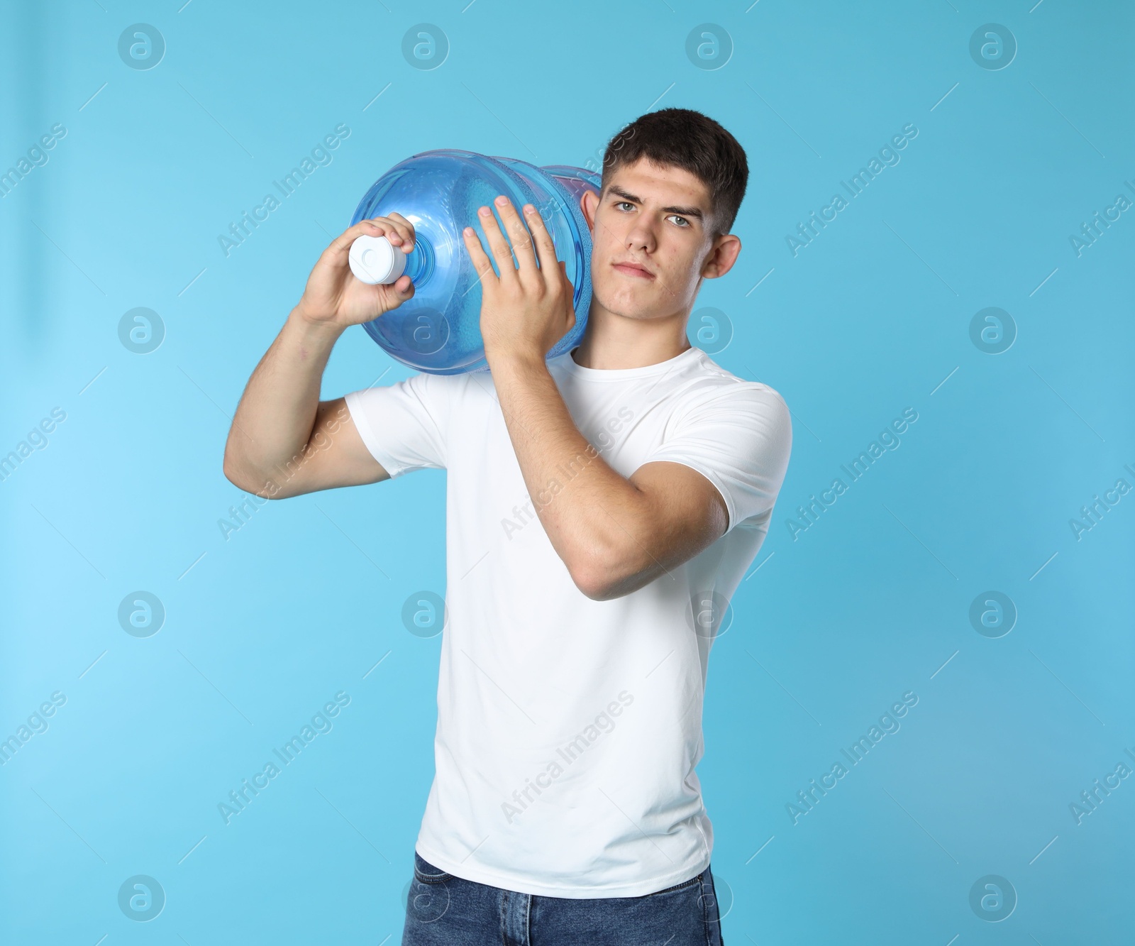 Photo of Delivery man with cooler bottle of water on light blue background