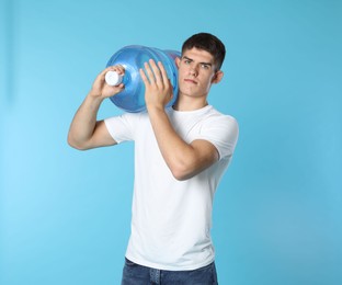 Photo of Delivery man with cooler bottle of water on light blue background