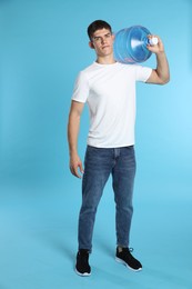 Photo of Delivery man with cooler bottle of water on light blue background
