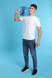 Photo of Delivery man with cooler bottle of water on light blue background