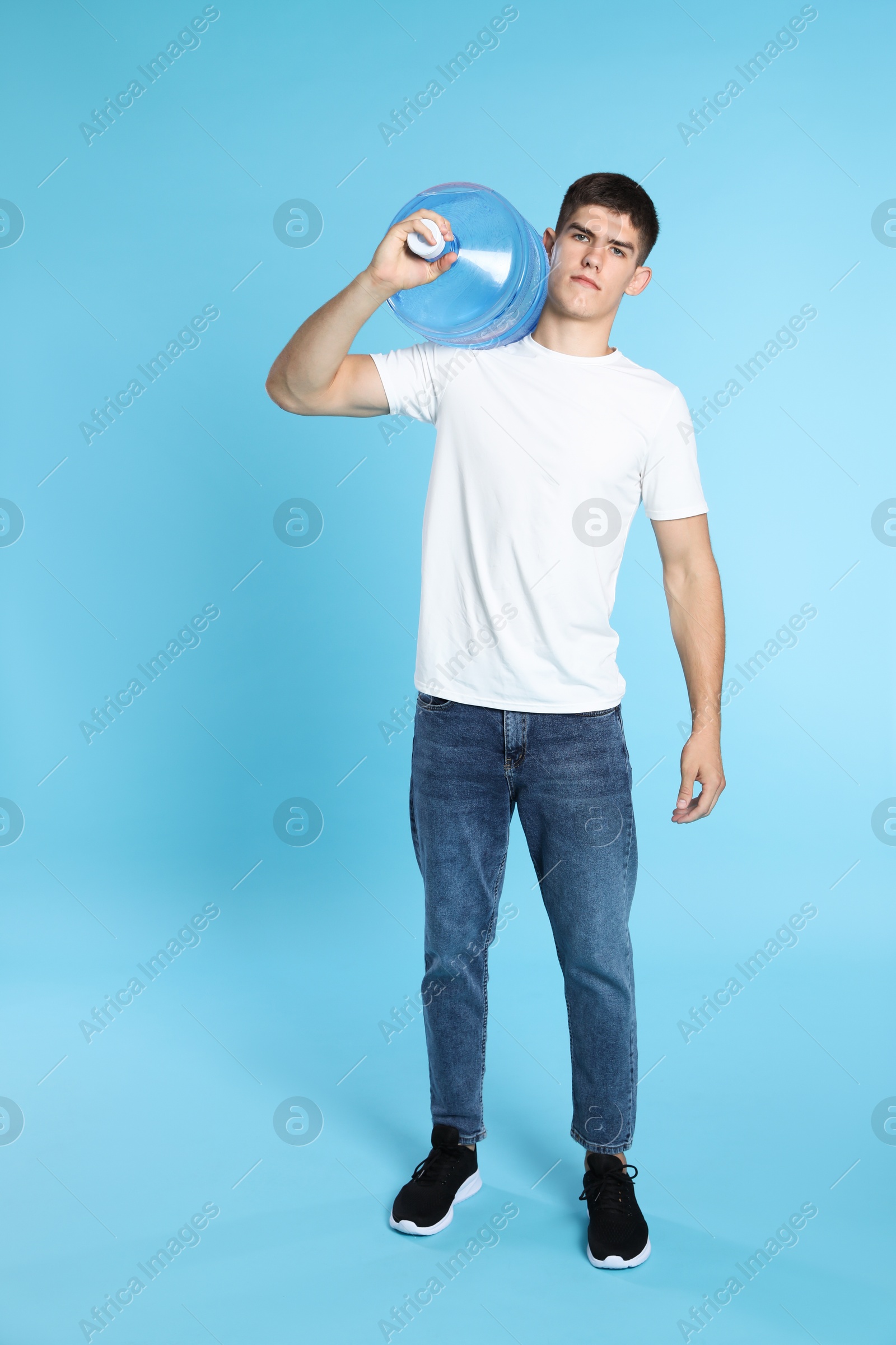 Photo of Delivery man with cooler bottle of water on light blue background