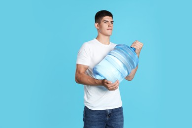 Photo of Delivery man with cooler bottle of water on light blue background