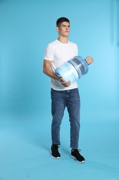 Photo of Delivery man with cooler bottle of water on light blue background