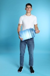 Photo of Delivery man with cooler bottle of water on light blue background