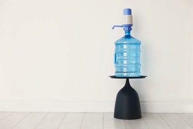 Photo of Cooler bottle with water and pump near white wall. Space for text