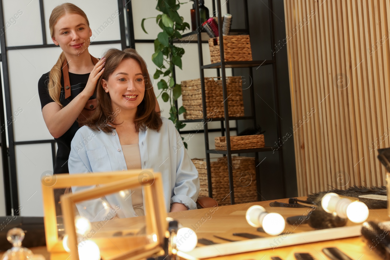 Hairstylist working with client near mirror in salon Photo of Hairstylist working with client near mirror in salon