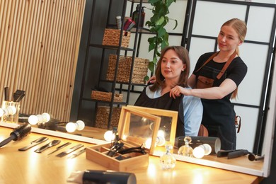 Photo of Hairstylist working with client near mirror in salon