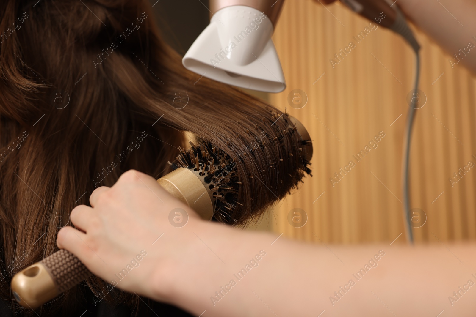 Photo of Hairstylist blow drying client's hair in salon, closeup