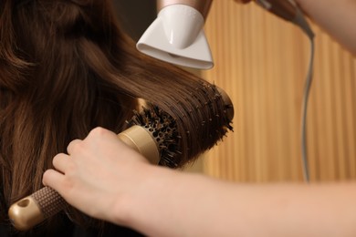 Photo of Hairstylist blow drying client's hair in salon, closeup