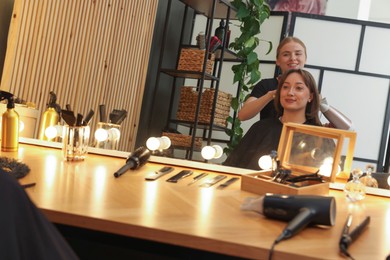 Photo of Hairstylist blow drying client's hair in salon