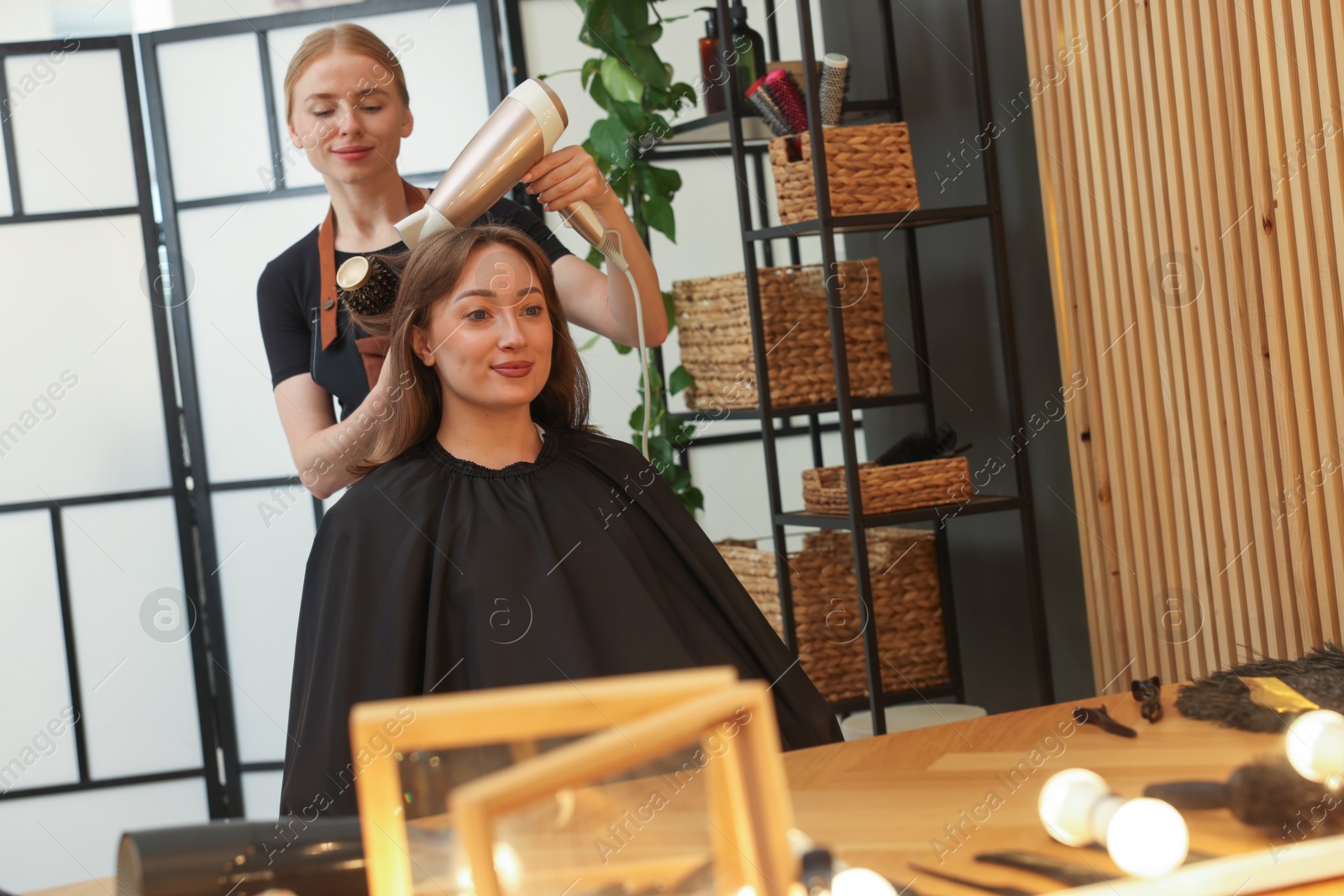 Hairstylist blow drying client's hair in salon Photo of Hairstylist blow drying client's hair in salon