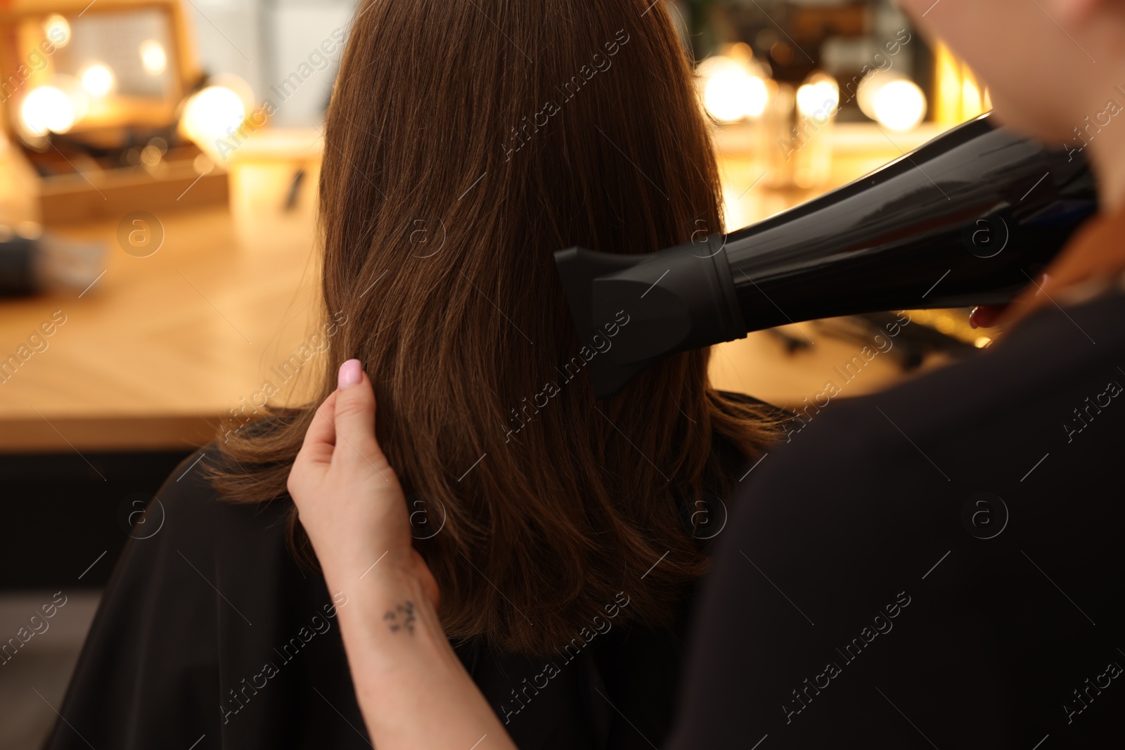 Hairstylist blow drying client's hair in salon, closeup Photo of Hairstylist blow drying client's hair in salon, closeup