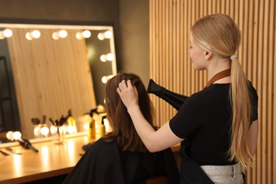 Photo of Hairstylist blow drying client's hair in salon