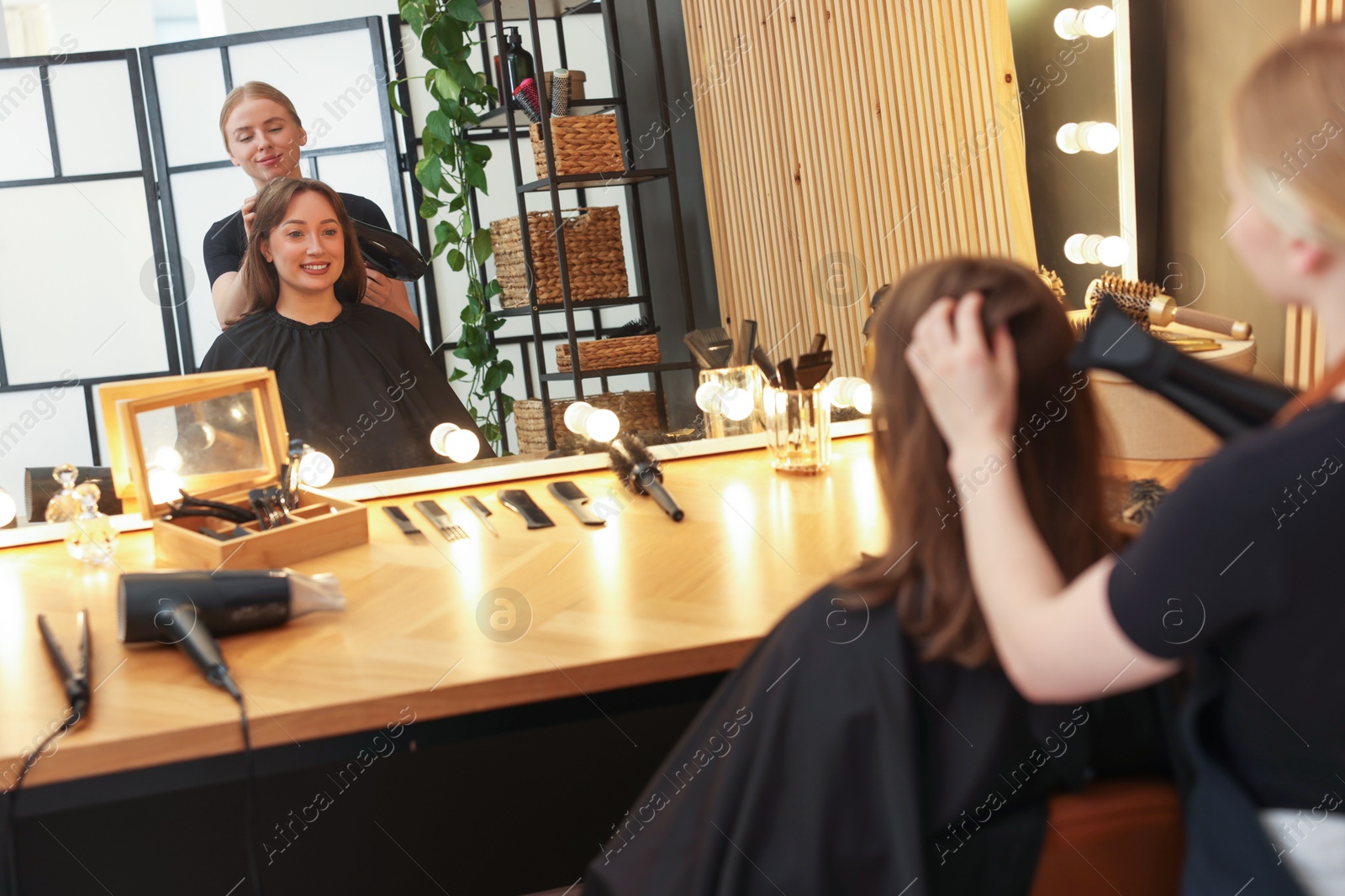 Hairstylist blow drying client's hair in salon Photo of Hairstylist blow drying client's hair in salon