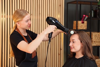 Photo of Hairstylist blow drying client's hair in salon