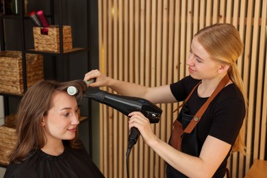 Photo of Hairstylist blow drying client's hair in salon