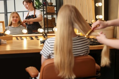 Photo of Professional hairstylist combing woman's hair in salon