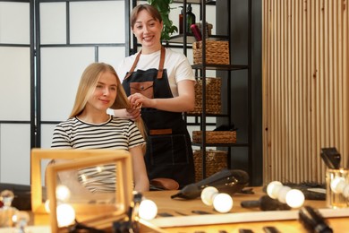 Photo of Professional hairstylist combing woman's hair in salon