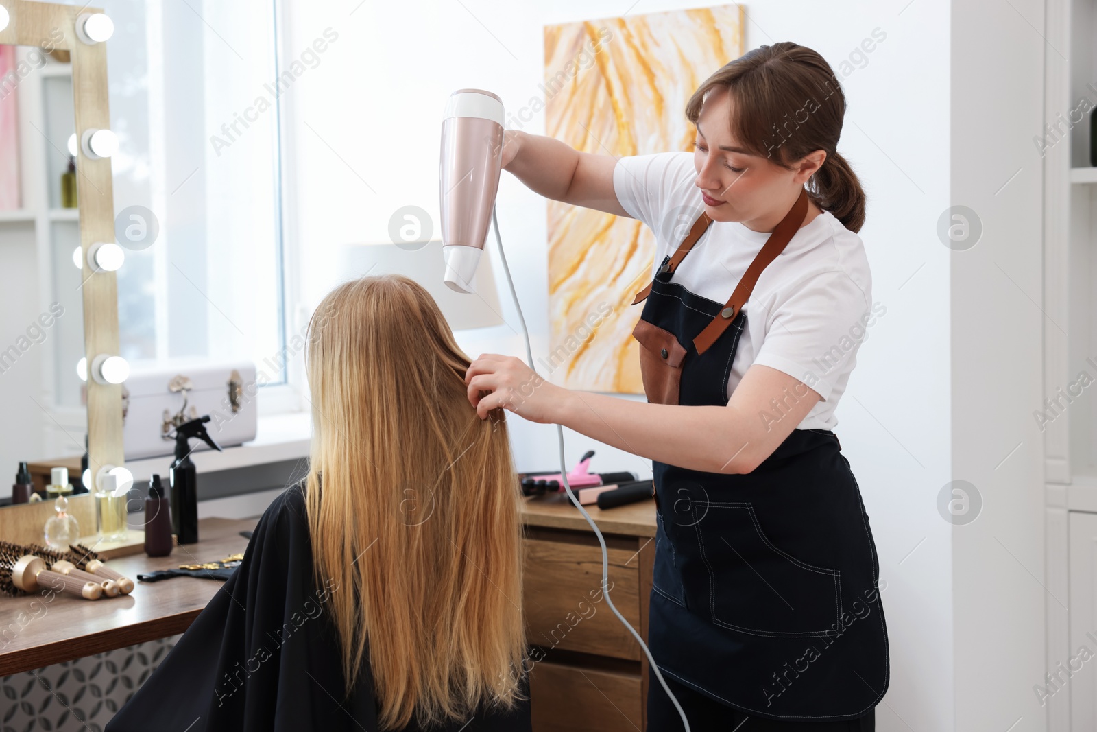 Photo of Hairstylist blow drying client's hair in salon