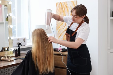 Photo of Hairstylist blow drying client's hair in salon