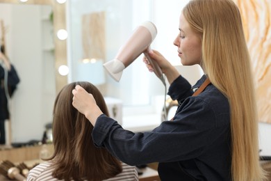 Photo of Hairstylist blow drying client's hair in salon