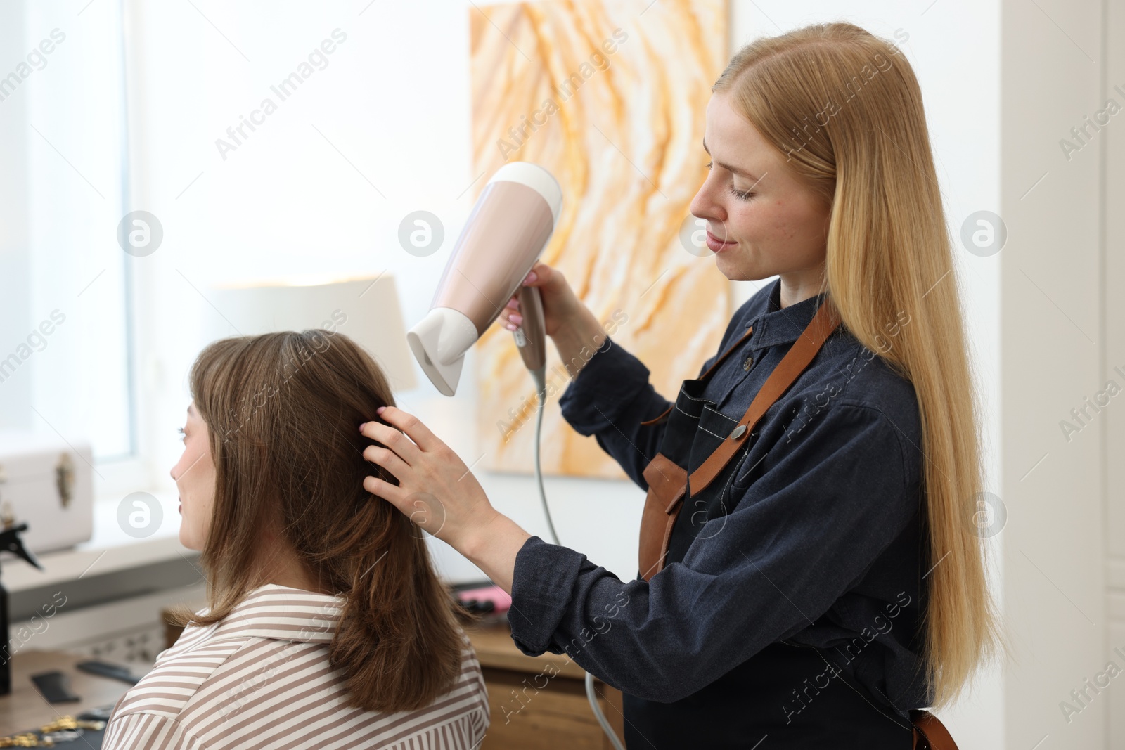 Photo of Hairstylist blow drying client's hair in salon