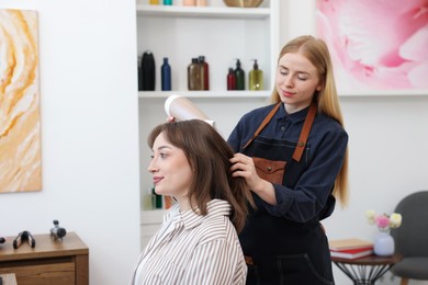 Photo of Hairstylist blow drying client's hair in salon