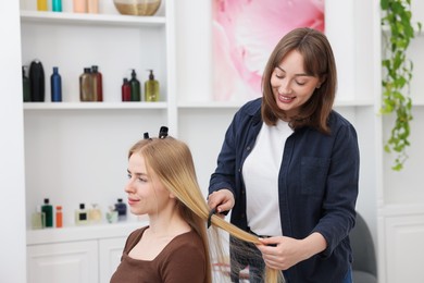 Photo of Professional hairstylist combing woman's hair in salon
