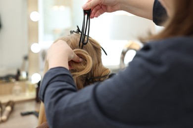 Photo of Professional hairstylist working with client in salon, closeup
