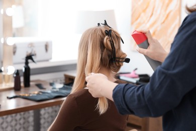 Photo of Professional hairstylist working with client in salon, closeup