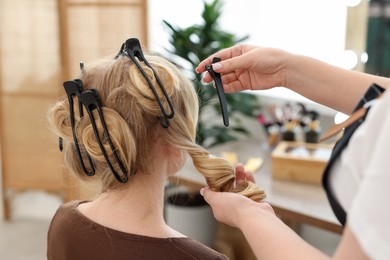Photo of Professional hairstylist working with client in salon, closeup