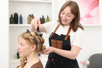 Photo of Professional hairstylist working with client in salon