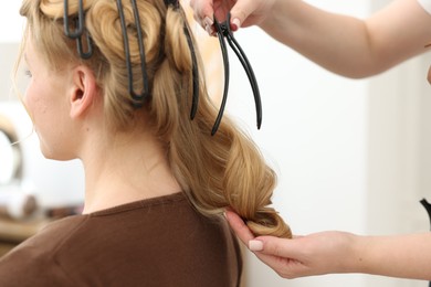 Photo of Professional hairstylist working with client in salon, closeup