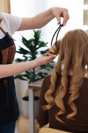 Photo of Professional hairstylist working with client in salon, closeup