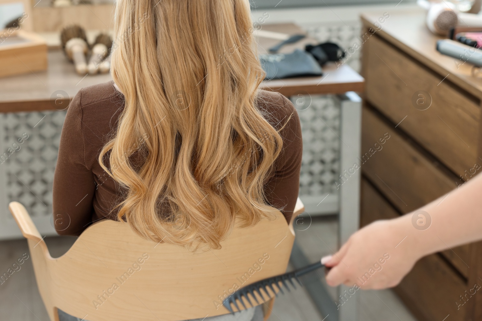 Professional hairstylist combing woman's hair in salon, closeup Photo of Professional hairstylist combing woman's hair in salon, closeup