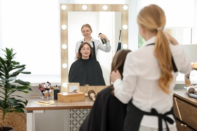 Photo of Professional hairstylist working with client in salon