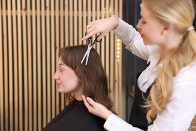 Photo of Hairstylist cutting client's hair with scissors in salon