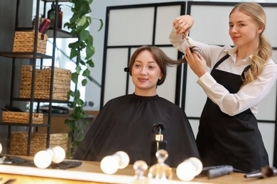 Photo of Hairstylist cutting client's hair with scissors in salon
