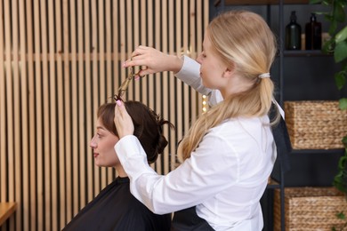 Photo of Hairstylist cutting client's hair with scissors in salon