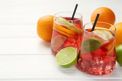 Photo of Tasty punch with ice, mint and slices of fruits in glasses on white wooden table, closeup with space for text. Refreshing drink