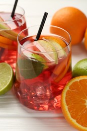 Photo of Tasty punch with ice, mint and slices of fruits in glasses on white wooden table, closeup. Refreshing drink
